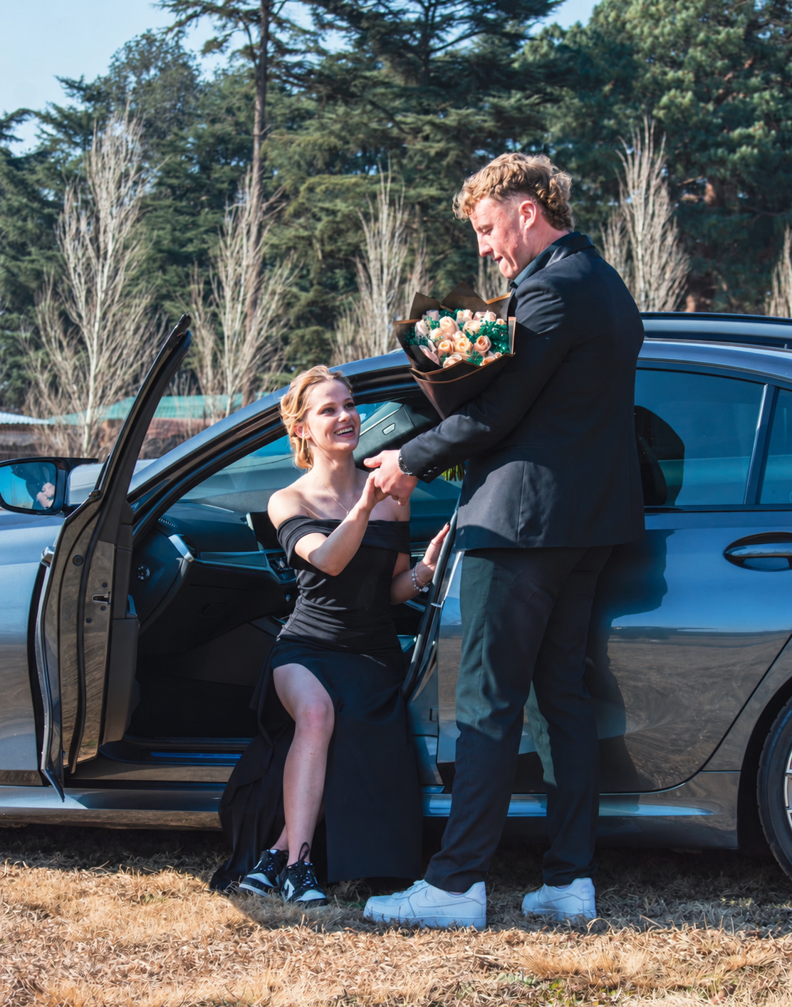 Matric farewell couple with flowers beside a car
