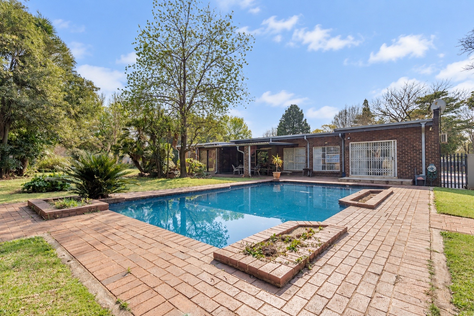 Brick house exterior with a swimming pool and garden