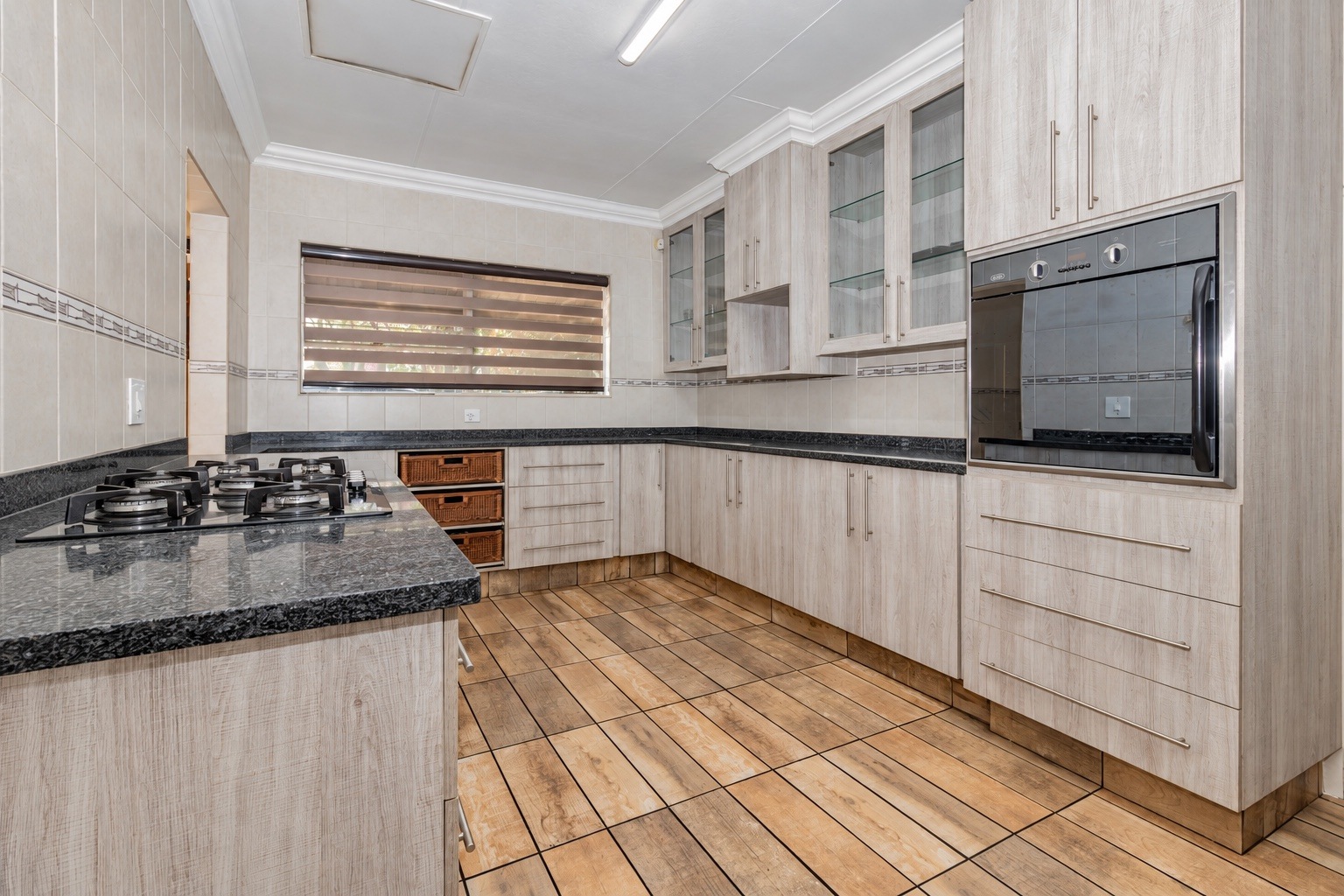 Kitchen with light wood cupboards, granite worktops and a gas hob