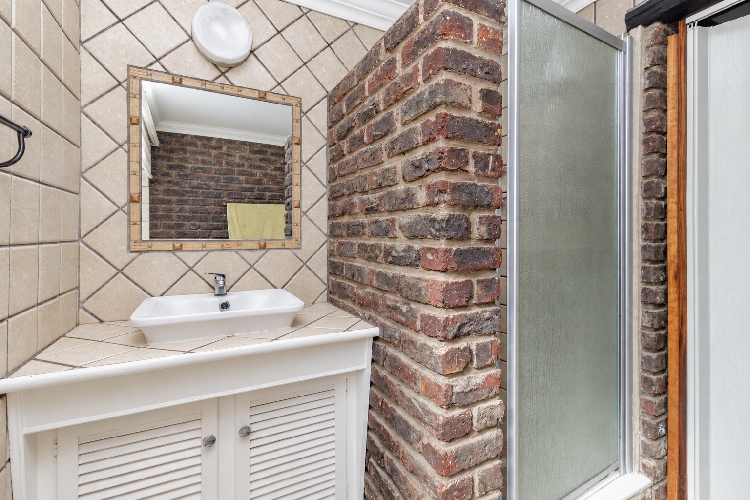 Bathroom vanity and shower with exposed brick detailing